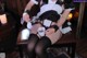 A woman in a maid outfit sitting on a chair holding a cup of coffee.