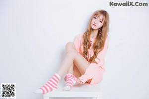 A woman sitting on top of a white table wearing pink and white striped socks.