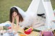 A woman in a white dress sitting on a picnic blanket.