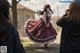 A woman in a red and white dress is taking a picture of another woman.