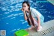 A young woman sitting on the edge of a swimming pool.