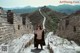 A woman standing on the side of a stone wall.