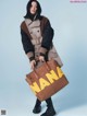 A woman holding a brown bag with the word NANA written on it.