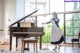 A woman in a maid outfit standing next to a piano.