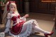 A woman in a red and white dress sitting on the floor.