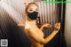 A naked woman wearing a face mask in a shower.